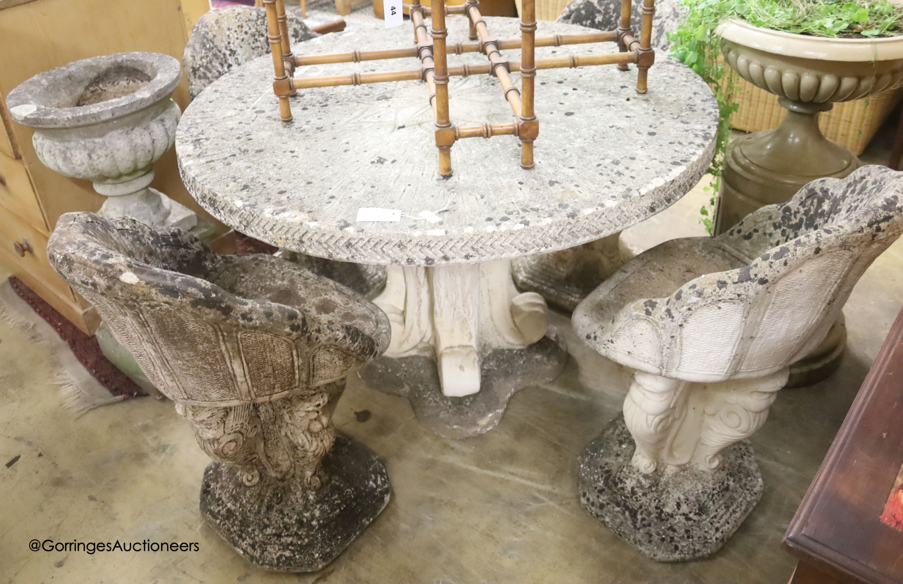 A circular reconstituted stone circular garden table, diameter 114cm, height 79cm and four matching chairs
